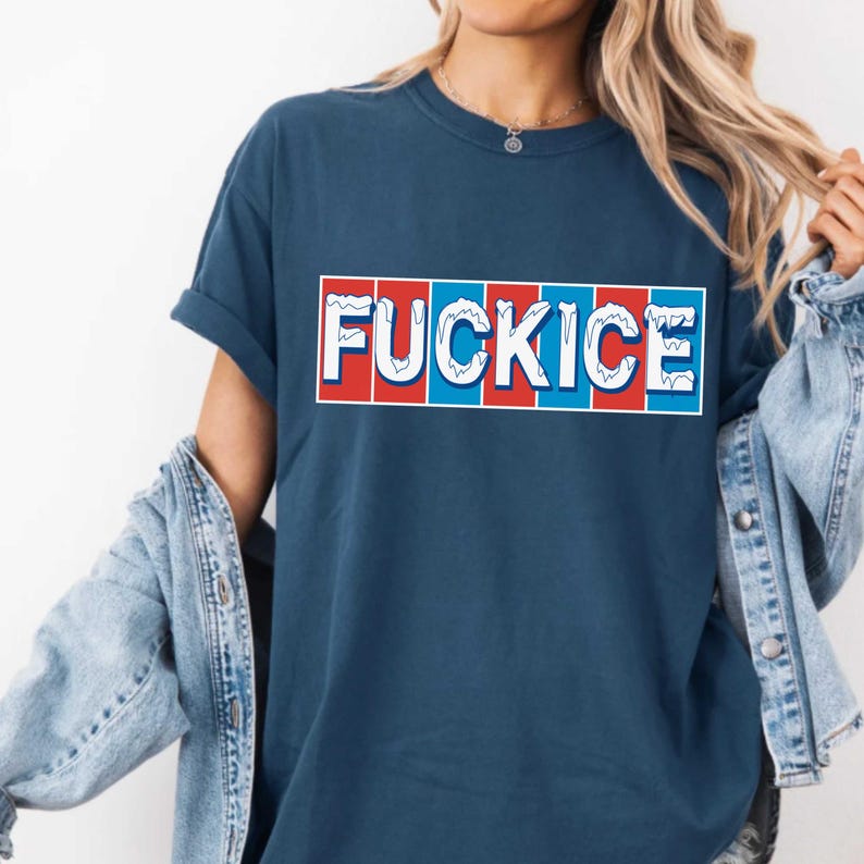 May include: A navy blue t-shirt with the word "FUCKICE" in white, set against a red and blue striped background. The shirt has rolled-up sleeves and is paired with a denim jacket.