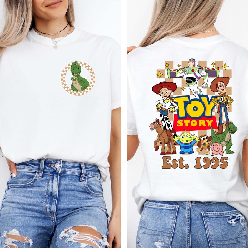 May include: White t-shirt featuring a green dinosaur graphic inside a brown and white checkered circle on the front. The back of the shirt displays a colorful Toy Story graphic with the text "Toy Story Est. 1995".
