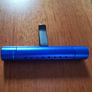 May include: A blue car air freshener with a black clip. The air freshener has a perforated design and is made of metal.