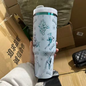 Peut inclure: Gobelet isotherme blanc avec des illustrations de Spider-Man et des toiles d'araign&eacute;es. Le gobelet a un couvercle blanc avec un accent turquoise et un bord argent&eacute;. Il peut contenir environ 887 ml.