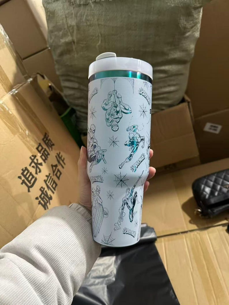 Peut inclure: Gobelet isotherme blanc avec des illustrations de Spider-Man et des toiles d'araign&eacute;es. Le gobelet a un couvercle blanc avec un accent turquoise et un bord argent&eacute;. Il peut contenir environ 887 ml.