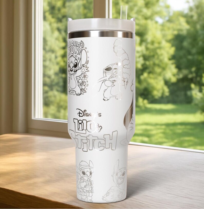 May include: White insulated tumbler featuring line art illustrations of Stitch from Lilo & Stitch. The tumbler includes the text "Aloha Fun!" and "Disney's Lilo & Stitch". It has a white lid and a clear straw. The tumbler is on a wooden surface.