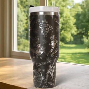May include: Black insulated tumbler featuring multiple Spider-Man illustrations and spiderwebs in a silver color. The tumbler has a white lid and a clear straw. The words "Spider-Man" are also visible on the tumbler.