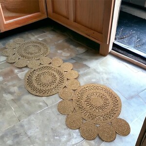 Puede incluir: Tres alfombras redondas de yute tejido con un patr&oacute;n circular de color marr&oacute;n claro. Las alfombras est&aacute;n dispuestas en fila, con la alfombra m&aacute;s grande en la parte posterior y la m&aacute;s peque&ntilde;a en la parte delantera.