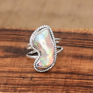 May include: A silver ring with a large, iridescent opal stone set in a twisted rope design.