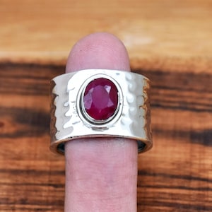 Peut inclure: Une bague en argent avec une finition martelée et une grande pierre de rubis ovale.