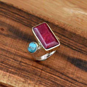 May include: A silver ring with a large rectangular red gemstone and a smaller round turquoise gemstone.