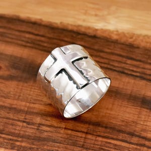 以下が含まれることがあります： ハンマーで叩いたような質感と、浮き上がった十字架のデザインが施されたシルバーリングです。