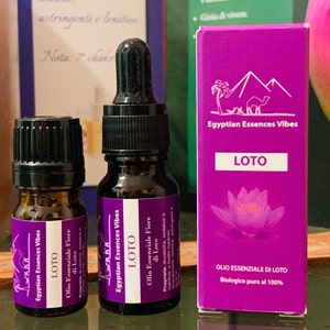 Può includere: Due piccoli flaconi di olio essenziale con etichette viola e contagocce neri. Le etichette riportano "Egyptian Essences Vibes" e "LOTO" con il testo "Olio Essenziale Fiore di Loto" sotto. I flaconi sono posizionati davanti a una scatola viola più grande con lo stesso marchio e il testo "Olio Essenziale di Loto Biologico puro al 100%".