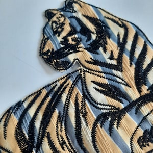 Op de afbeelding: Een geborduurde tijgerpatch in zwart en wit met een gestreept patroon. De tijger kijkt naar rechts en heeft een gedetailleerd ontwerp.