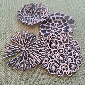 Peut inclure: Quatre appliques en dentelle noire et rose avec des motifs complexes. Les appliques sont faites d'un tissu délicat et ont un aspect délicat et féminin.