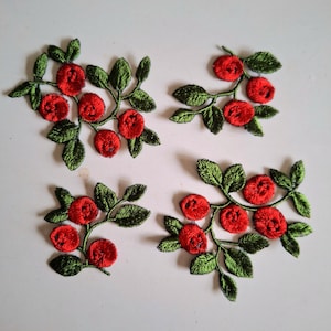 Peut inclure: Quatre écussons en tissu brodé représentant des grappes de baies rouge vif et de feuilles vert foncé. Chaque écusson présente une disposition unique de fruits ronds rouges fixés sur de fines tiges avec un feuillage détaillé en relief.