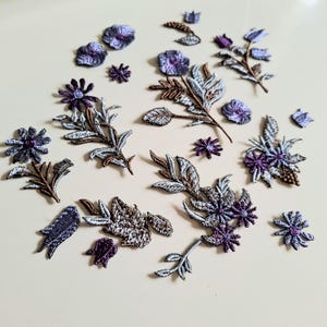Puede incluir: Colección de apliques florales bordados en varios tamaños y diseños. Los apliques presentan tonos de morado, marrón y plateado, con costuras detalladas. Estos parches decorativos son ideales para embellecer ropa, accesorios o proyectos de manualidades.