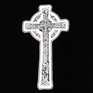 May include: A white Celtic cross with intricate knotwork design. The cross is outlined in white and has a circular halo around it.