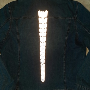 May include: A dark blue denim jacket with a white reflective strip down the back.