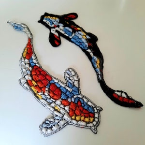 May include: Two embroidered iron-on patches of koi fish. One fish is red, yellow, blue, and white. The other fish is black, blue, and yellow.