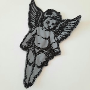 May include: Black and gray embroidered iron-on patch of a cherub angel with wings.