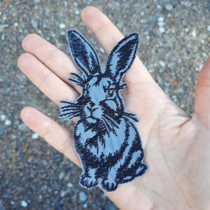 以下が含まれることがあります： 長い耳とひげのある黒いウサギのグレーの刺繍アイロン接着パッチ