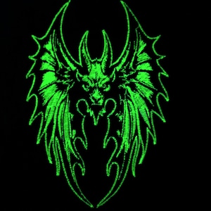 May include: Green glow-in-the-dark embroidered patch of a dragon with wings spread wide.