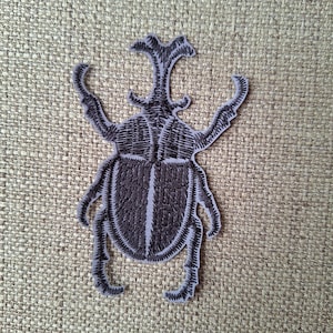 Reflekterande noshörningsbagge stryklapp