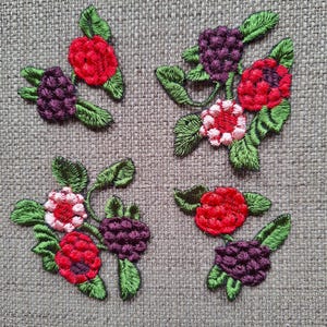 May include: Five embroidered patches featuring red, pink, and purple berries with green leaves. The patches are on a brown burlap background.