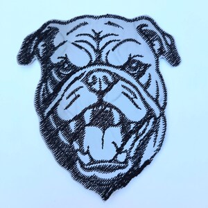 Peut inclure: Patch brodé en noir et blanc représentant la tête d'un bouledogue avec la bouche ouverte montrant les dents.