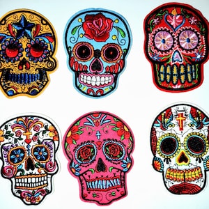 Peut inclure: Six écussons brodés en forme de crânes colorés. Chaque crâne présente des motifs floraux et décoratifs complexes, avec des couleurs vives comme le rouge, le bleu, le jaune et le rose. Idéal pour personnaliser des vêtements ou des accessoires.