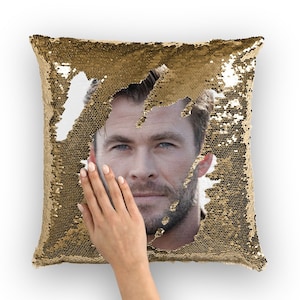 May include: A gold sequin pillow with a hidden image of a man's face. The sequins can be flipped to reveal the image.