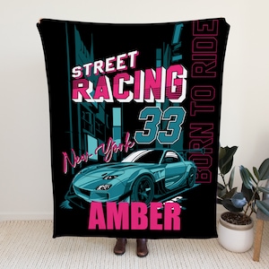Könnte beinhalten: Eine schwarze Fleece-Decke mit einer blauen Auto-Illustration und dem Text "Street Racing 33 Born to Ride" in Pink. Der Name "Amber" ist ebenfalls in Pink am unteren Rand der Decke aufgedruckt.