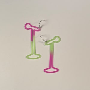 May include: A pair of earrings in the shape of a microphone stand. The earrings are outlined in a gradient of pink and green, with silver-colored ear wires. The design is minimalist and modern, suitable for music lovers.