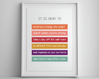 Op de afbeelding: Een wit ingelijst print met de tekst "IT IS OKAY TO" in zwart. De tekst wordt gevolgd door zes gekleurde strepen met de volgende tekst: "embrace change and adapt", "admit when you're wrong", "take a day off for self-care", "be different from everyone else", "seek happiness on your own terms", en "take time to heal after a loss".