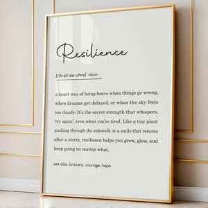 May include: A framed print with a gold border. The print features the word "Resilience" in elegant script above a definition. The definition is in black text on a white background. The definition includes the pronunciation and related terms.
