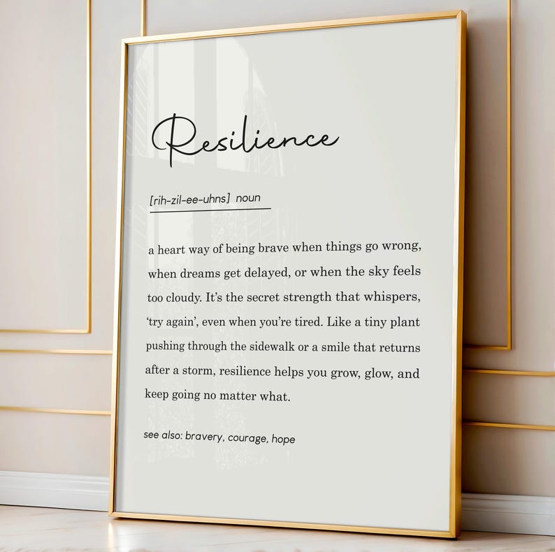 May include: A framed print with a gold border. The print features the word "Resilience" in elegant script above a definition. The definition is in black text on a white background. The definition includes the pronunciation and related terms.