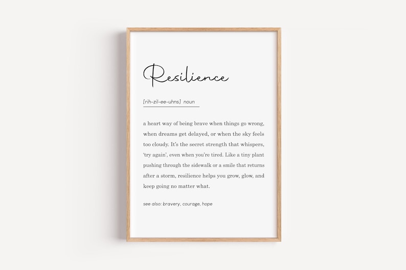 May include: A framed print with the definition of "Resilience" in black text on a white background. The definition includes the pronunciation and a description of resilience. The frame is a light brown color.