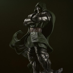 May include: A detailed collectible figurine of a character wearing a metallic silver mask, dark armor plating on the arms and legs, and a flowing dark green hooded cloak. The figure stands on a textured, dark rocky base with arms crossed.