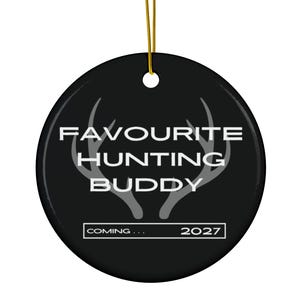 Op de afbeelding: Een rond zwart keramisch ornament met een gouden ophangkoord. Het ontwerp bevat een lichtgrijze afbeelding van een hertengewei met de witte tekst FAVORITE HUNTING BUDDY en een rechthoekig kader met de tekst COMING... 2027.