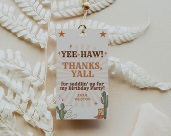 May include: A white card with a brown and orange design. The card says "Yee-Haw! Thanks, Y'all" and "for saddlin' up for my Birthday Party!" with a cactus and cowboy boot illustration. The card is tied with a gold tassel.