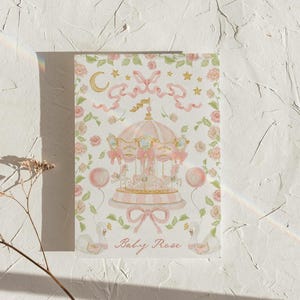 May include: A pink and gold carousel with white horses and pink ribbons. The carousel is surrounded by pink flowers and green leaves. The text "Baby Rose" is written below the carousel.