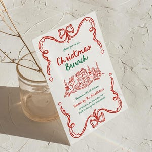 May include: A white Christmas Brunch invitation with red and green text and illustrations. The invitation features a red ribbon border and the words "Christmas Brunch". The invitation includes the date, time, and host information.