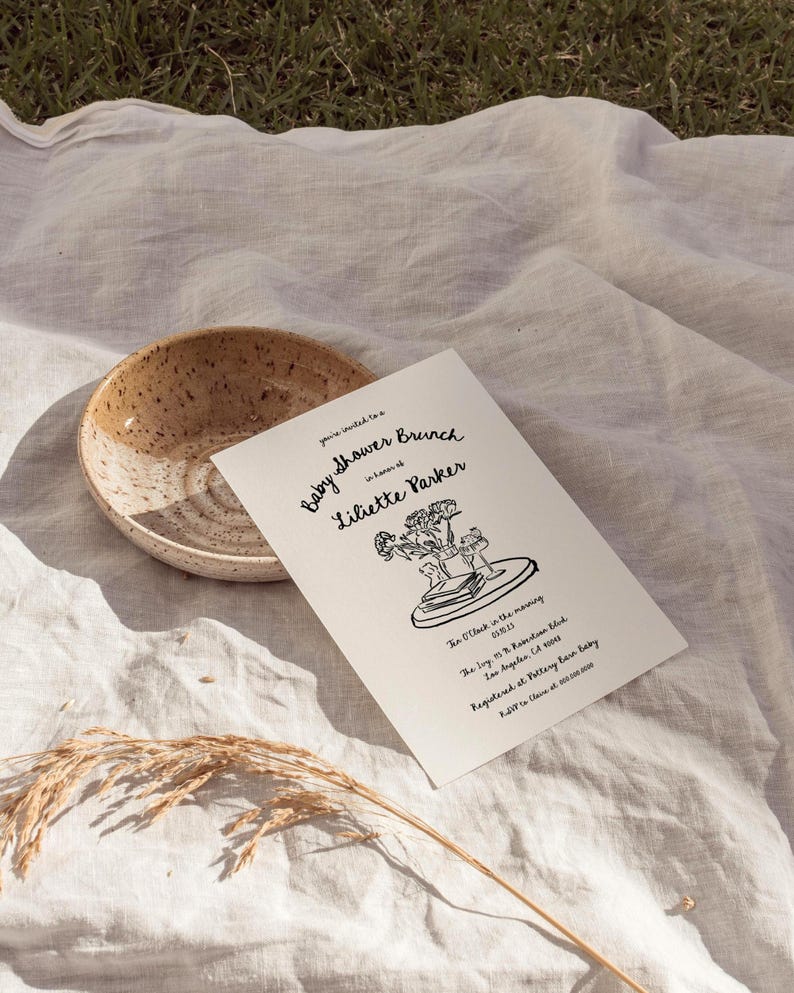 May include: A black and white illustration of a baby shower brunch invitation for Liliette Parker. The invitation includes the date, time, and location of the event. The illustration features a bouquet of flowers, a book, and a cup.