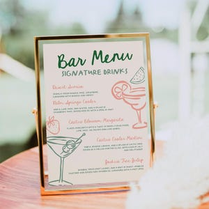May include: A gold-framed bar menu with a green and white handwritten title "Bar Menu" and a list of signature drinks with illustrations. The drinks include "Desert Sunrise", "Palm Springs Cooler", "Cactus Blossom Margarita", "Cactus Cooler Martini", and "Joshua Tree Julep".