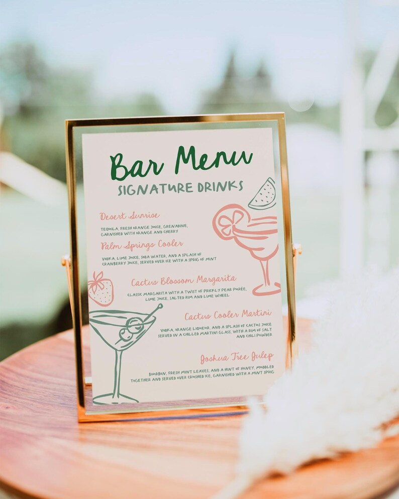 May include: A gold-framed bar menu with a green and white handwritten title "Bar Menu" and a list of signature drinks with illustrations. The drinks include "Desert Sunrise", "Palm Springs Cooler", "Cactus Blossom Margarita", "Cactus Cooler Martini", and "Joshua Tree Julep".