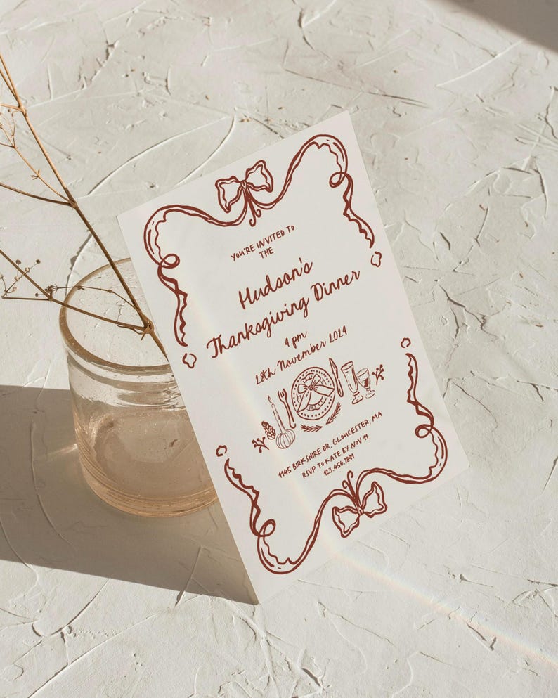 May include: A white invitation card with a red border and a red bow at the top. The text on the card reads "You're invited to the Hudson's Thanksgiving Dinner 4 pm 18th November 2014 1145 Birk Share Dr, Gloucester, MA RSVP to Kate by Nov 23.458.209".