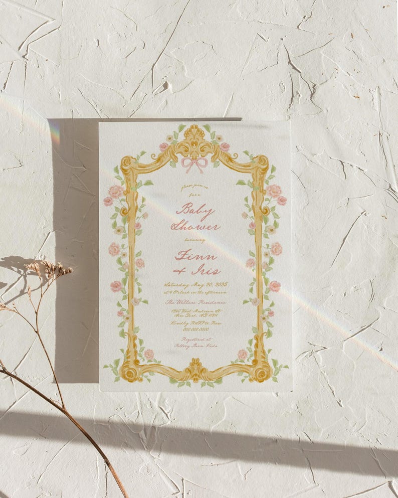 May include: A baby shower invitation with a gold ornate frame decorated with pink and green flowers. The text reads "Please join us for a Baby Shower honoring Finn of Iris Saturday, May 21, 2023 at 2 PM in the afternoon The Willow Residence 123 Main Street Anytown, USA RSVP by May 15th Registered at Baby Gear Store"