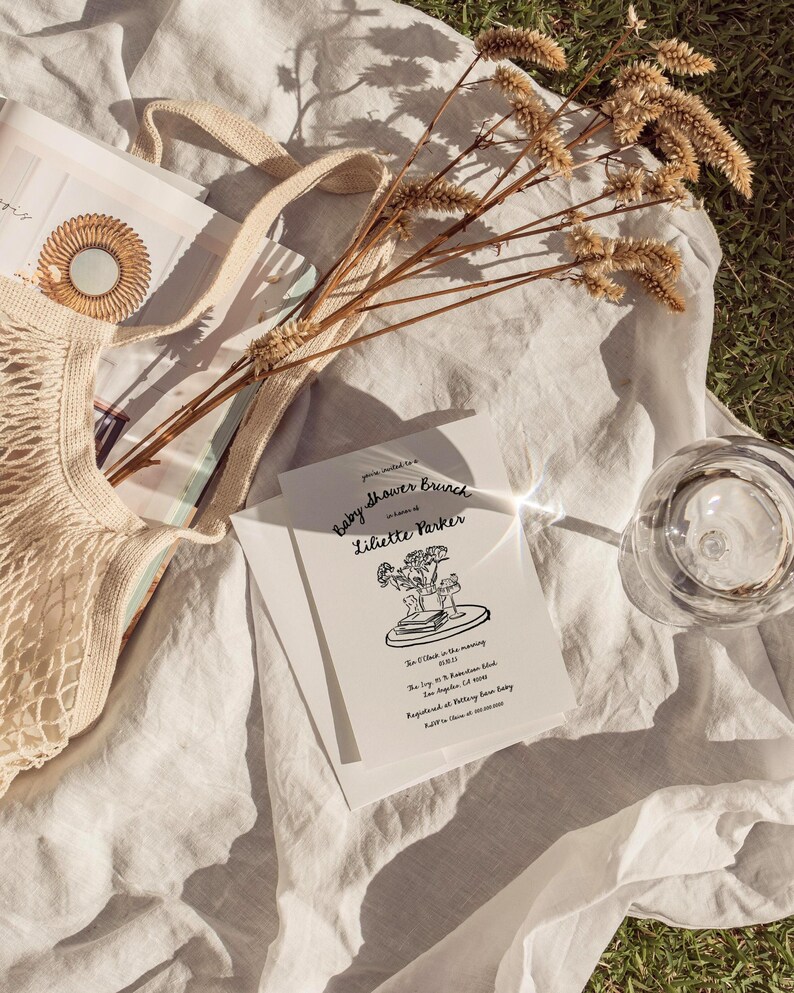 May include: A white invitation card with black text and a simple line drawing of a bouquet of flowers in a vase. The text reads "Baby Shower Brunch in honor of Liliette Parker. 10 o'clock in the morning.  July 10, 2023.  12345  Random Blvd. Los Angeles, CA 91234.  RSVP to:  Brittany Rose Baby.  Registry at:  Target.com.  R.S.V.P. by June 10, 2023."
