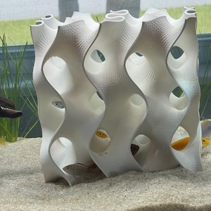 8x8 White 3D-printed gyroid aquarium cave in use, with fish hiding inside. The reef-safe design mimics coral structures, providing shelter and breeding spaces for cichlids, shrimp, and other pets. Enhances tank aesthetics and habitat.
