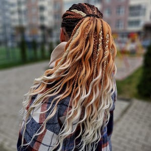 May include: A hairstyle featuring a mix of dark brown, ginger, and platinum blonde braided extensions. The hair is styled in a high ponytail with a combination of tight braids and loose, wavy strands that cascade down the back in a layered effect.