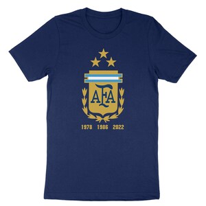 Op de afbeelding: Een marineblauw t-shirt met een gouden wapenschild met de letters "AFA" en vijf sterren. Het wapenschild is omringd door een lauwerkrans. De tekst "1978 1986 2022" is onder het wapenschild gedrukt.