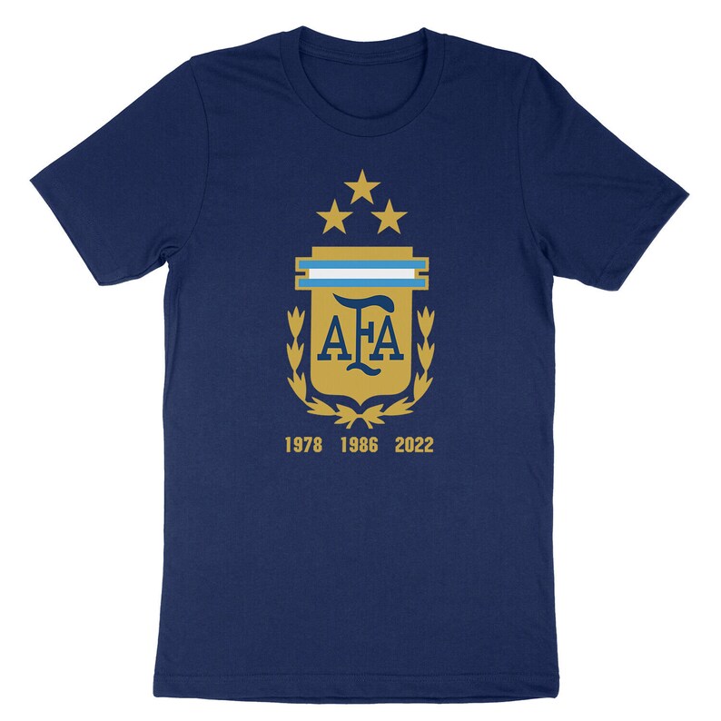 Op de afbeelding: Een marineblauw t-shirt met een gouden wapenschild met de letters "AFA" en vijf sterren. Het wapenschild is omringd door een lauwerkrans. De tekst "1978 1986 2022" is onder het wapenschild gedrukt.
