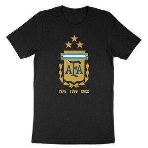 Op de afbeelding: Zwart T-shirt met een gouden wapenschild met de letters "AFA" en drie sterren. Het wapenschild is omringd door een lauwerkrans. De tekst "1978 1986 2022" is onder het wapenschild gedrukt.
